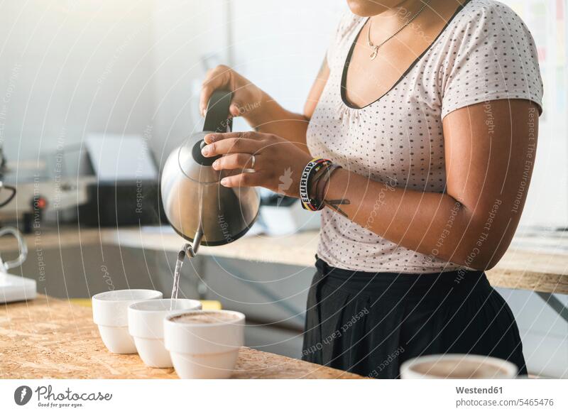 Close-up of woman working in a coffee roastery pouring hot water into coffee cups human human being human beings humans person persons Mixed Race