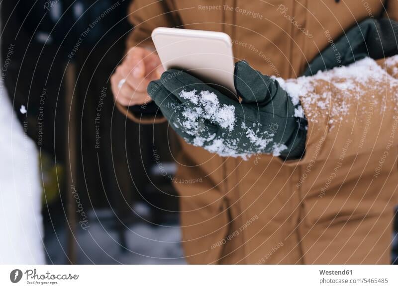 Man's hand holding smartphone in winter, close-up gloves telecommunication phones telephone telephones cell phone cell phones Cellphone mobile mobile phones
