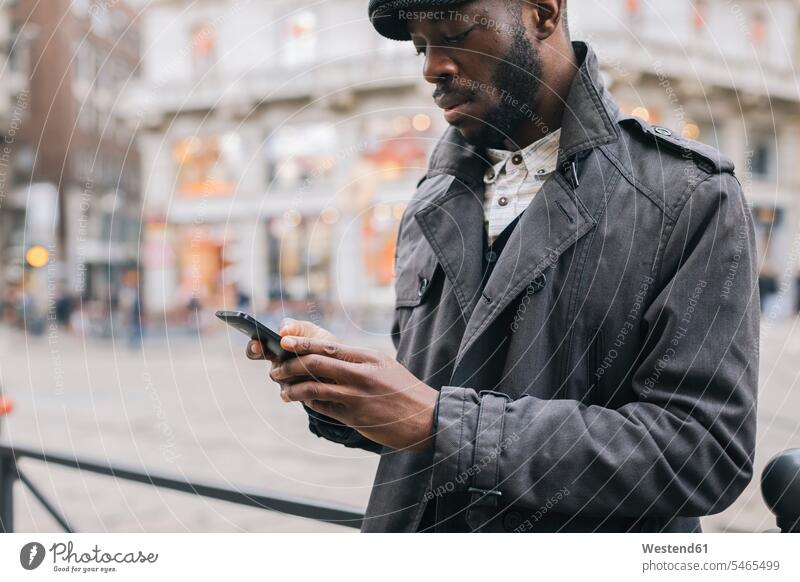Man in the city checking cell phone town cities towns mobile phone mobiles mobile phones Cellphone cell phones man men males outdoors outdoor shots