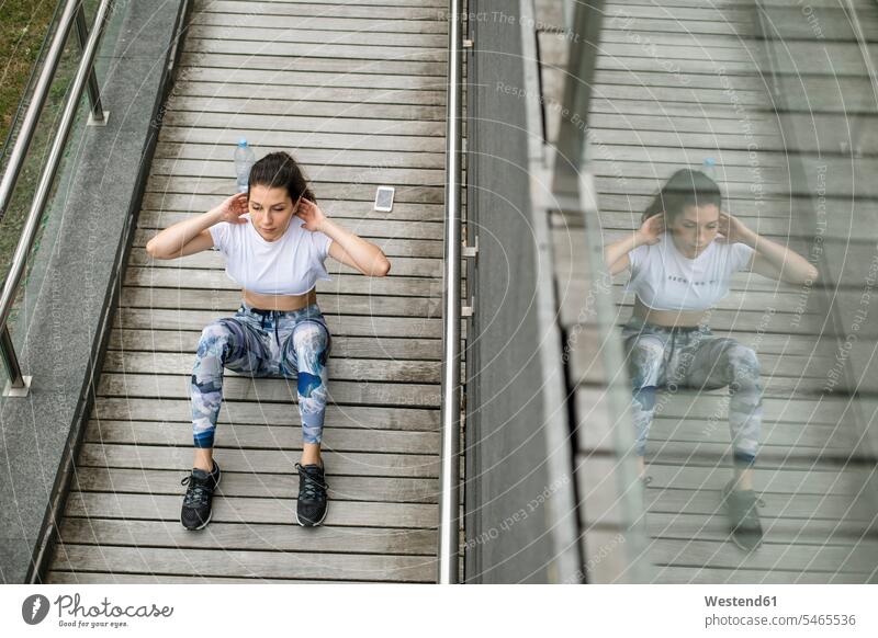 Young woman doing situps on a footbridge exercising exercise training practising females women sit-up sit-ups reflection reflexion Reflecting reflections