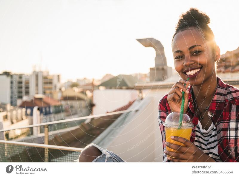 Portrait of happy young woman having a drink on rooftop at sunset human human being human beings humans person persons African black black ethnicity coloured 1