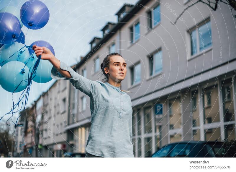 Portrait of young woman with blue balloons outdoors females women decoration decorating decorations colour colours Adults grown-ups grownups adult people
