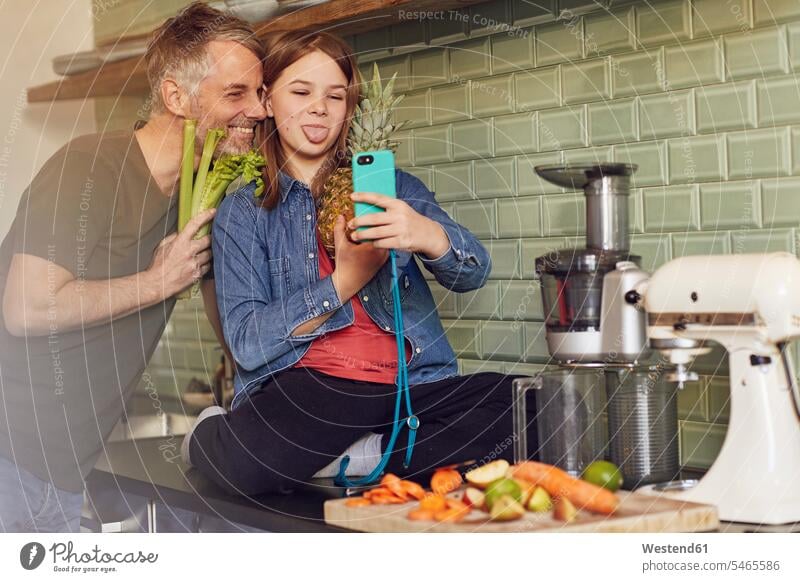 Happy father and daughter in kitchen making a selfie with fruit and vegetable photograph smile delight enjoyment Pleasant pleasure Cheerfulness exhilaration