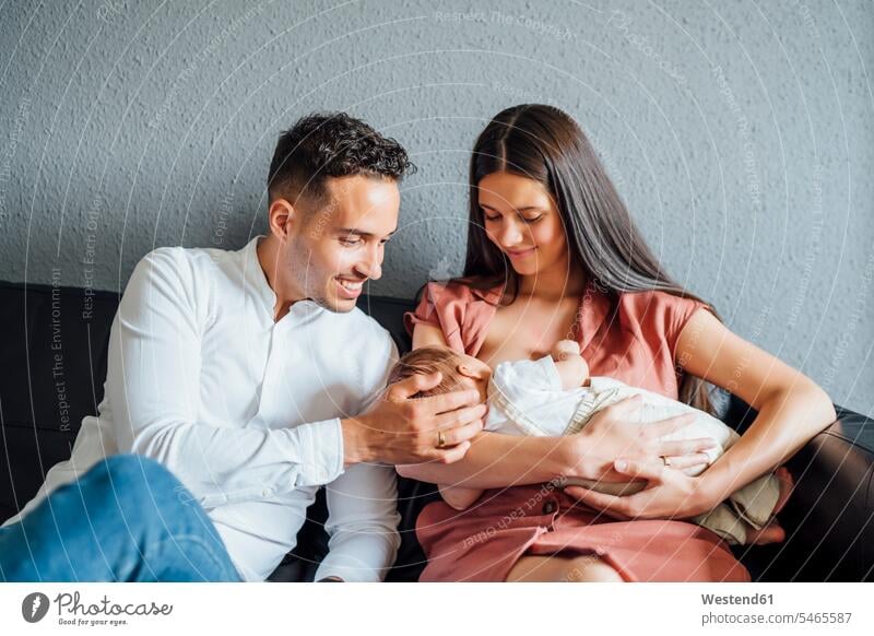 Happy father looking at baby boy being breastfed by mother at home color image colour image indoors indoor shot indoor shots interior interior view Interiors