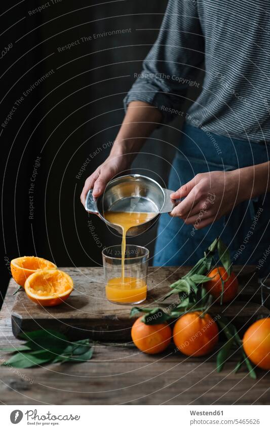 Young man pouring freshly squeezed orange juice into a glass, partial view young Orange Juice men males Fruit Juice Fruit Juices Drink beverages Drinks Beverage