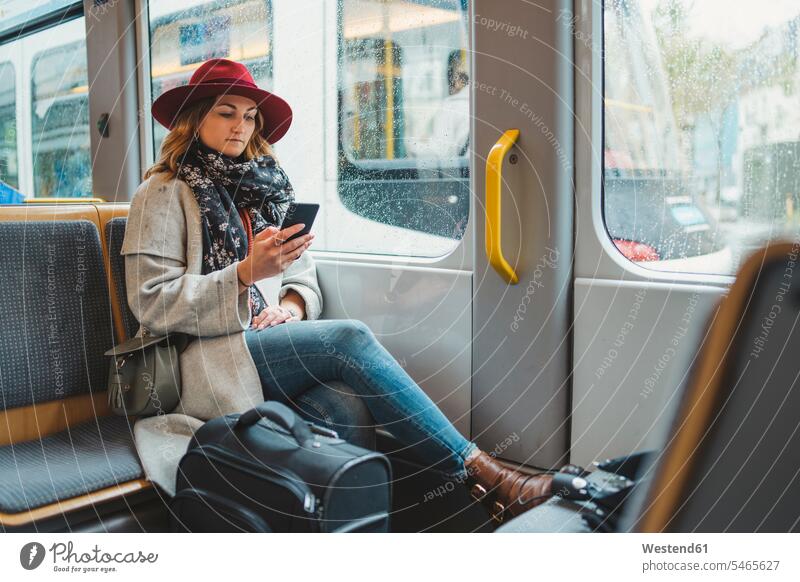 Young woman using cell phone in a tram luggage SMS Text Message human human being human beings humans person persons caucasian appearance caucasian ethnicity
