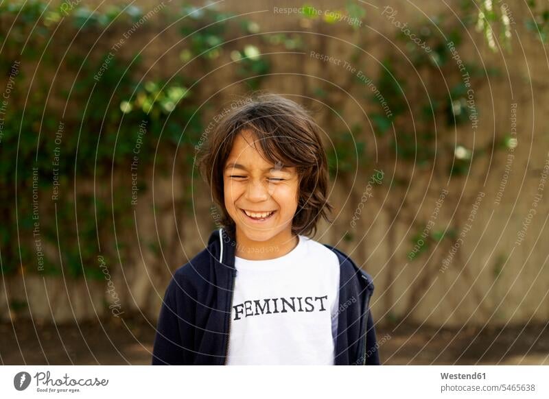Laughing boy standing in the street with print on t-shirt, saying Feminist T- Shirt t-shirts tee-shirt delight enjoyment Pleasant pleasure Cheerfulness