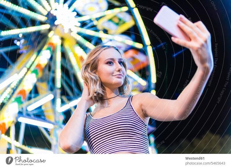 Portrait of teenage girl taking selfie in front of big wheel at fair Smartphone iPhone Smartphones funfairs kermis fairground fun fair fairgrounds fun fairs