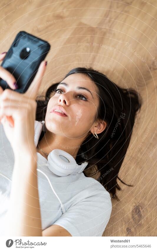 Young woman lying on the floor holding smartphone human human being human beings humans person persons caucasian appearance caucasian ethnicity european 1