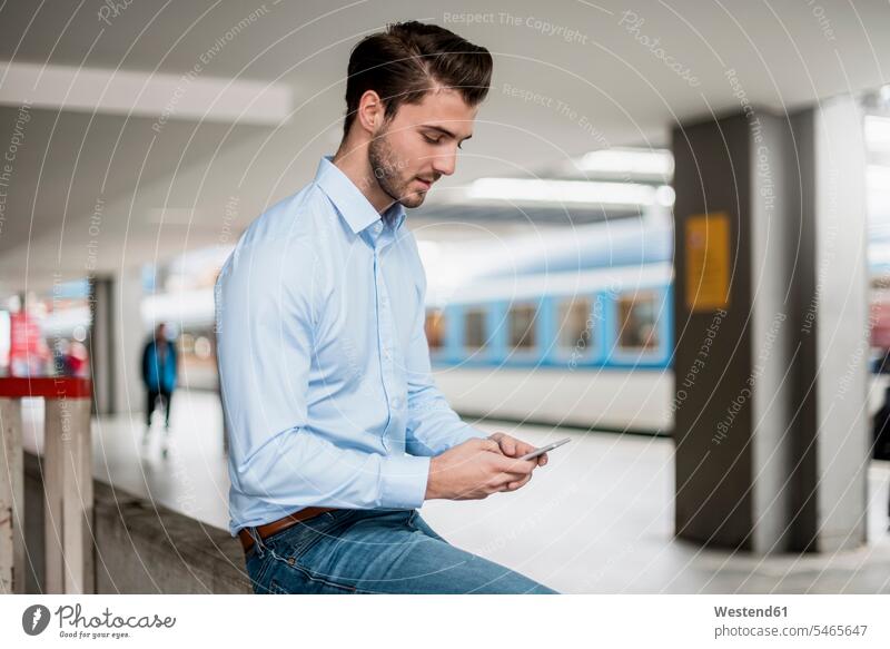 Businessman using cell phone at the station mobile phone mobiles mobile phones Cellphone cell phones Business man Businessmen Business men telephones