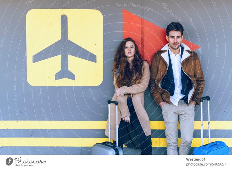 Confident business couple standing with luggage at airport terminal color image colour image indoors indoor shot indoor shots interior interior view Interiors