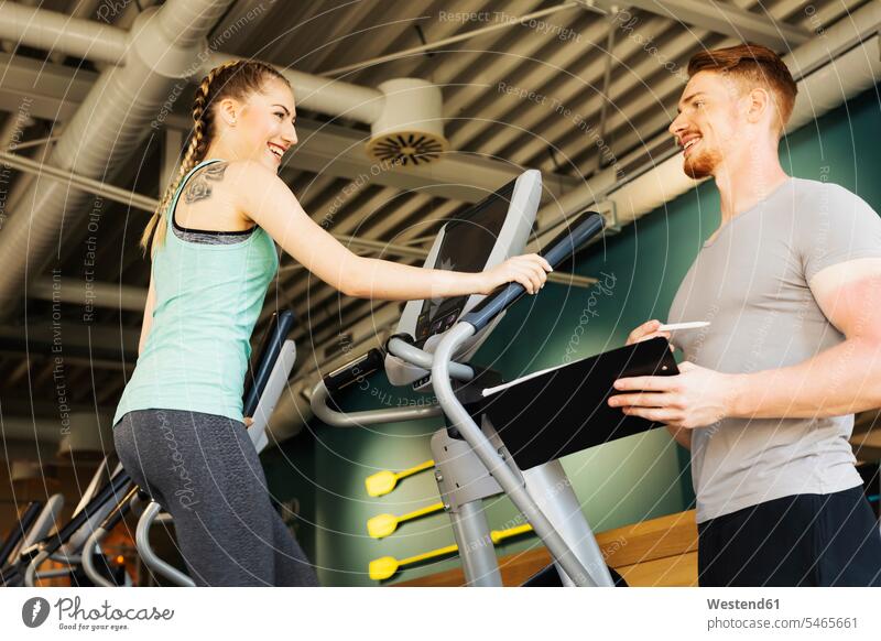 Young woman exercising on step machine in fitness gym with personal trainer human human being human beings humans persons caucasian appearance