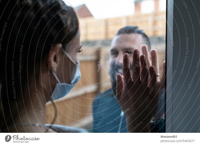 Couple touching hands from window glass during COVID-19 pandemic color image colour image day daylight shot daylight shots day shots daytime boyfriend