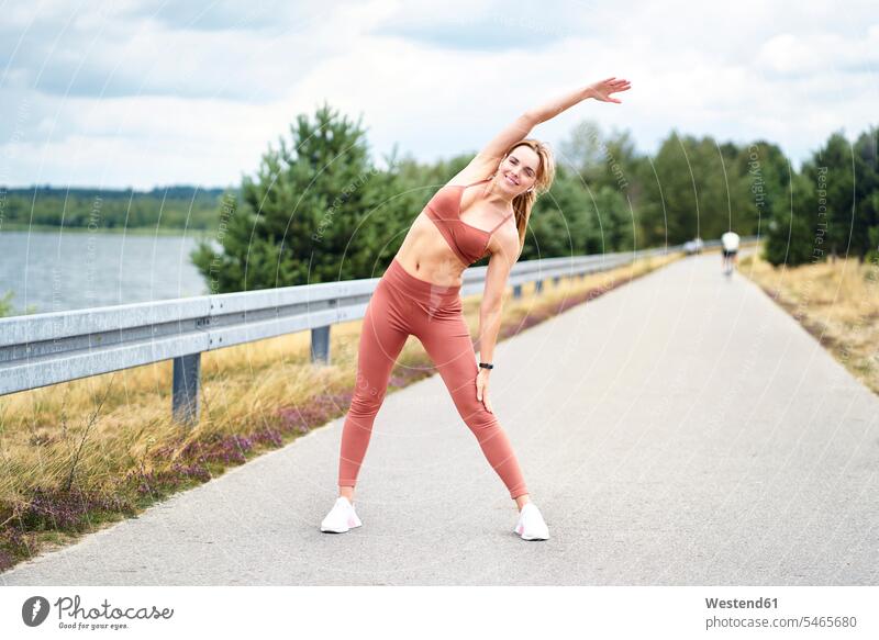 Woman stretching before outdoor training session smile summer time summertime summery delight enjoyment Pleasant pleasure Cheerfulness exhilaration gaiety gay