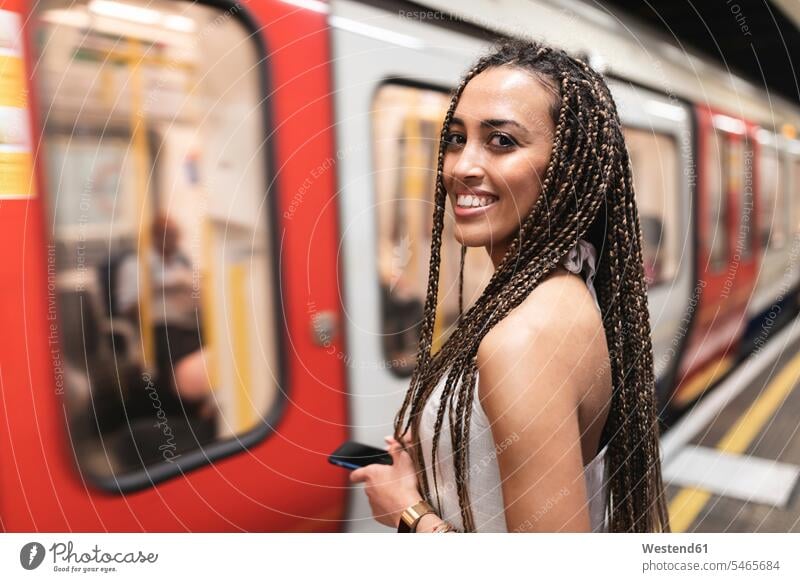Portrait of happy young woman waiting at subway station platform, London, UK human human being human beings humans person persons Mixed Race
