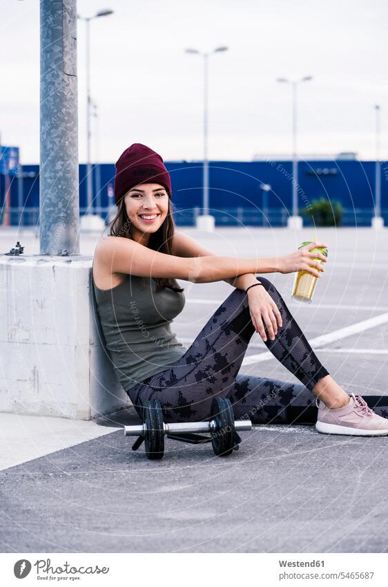Young woman sitting on ground after dumbbell training, drinking juice active Seated Taking a Break resting break fitness Strength strong Force Strengthy Power
