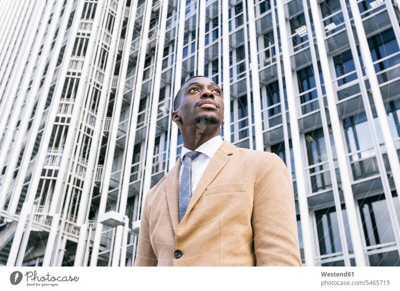 Young businessman in front of modern office building in the city looking sideways business life business world business person businesspeople Business man