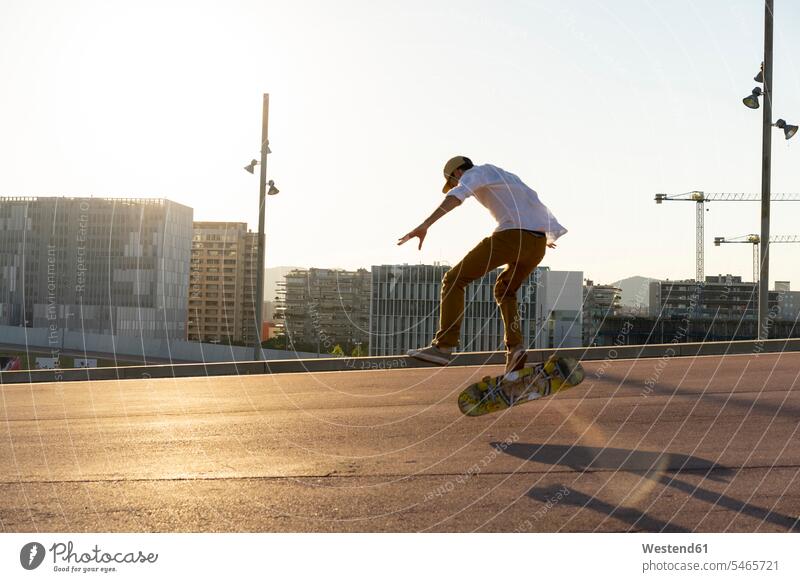 Young man riding skateboard in the city skateboarder skater skateboarders skaters town cities towns Skate Board skateboards men males people persons human being