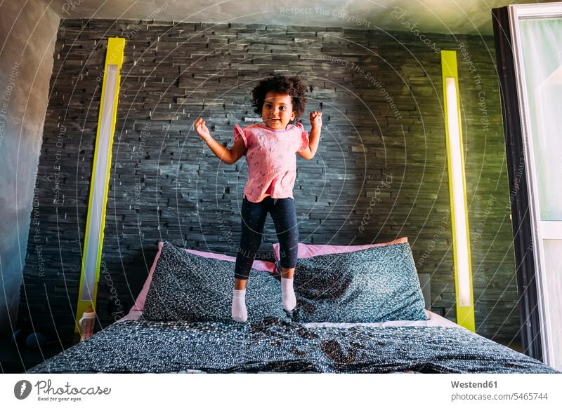 Playful baby girl jumping on bed at home color image colour image leisure activity leisure activities free time leisure time casual clothing casual wear