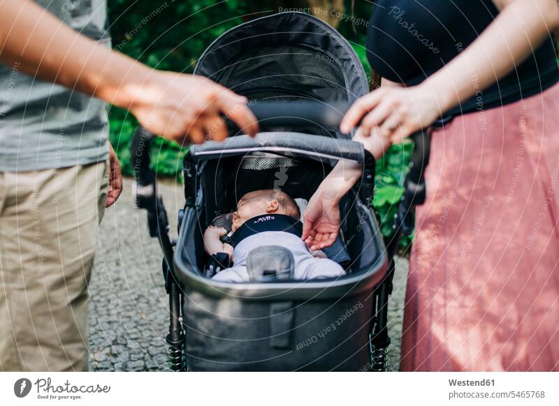 Parents standing by baby sleeping in carriage at park color image colour image Portugal outdoors location shots outdoor shot outdoor shots day daylight shot