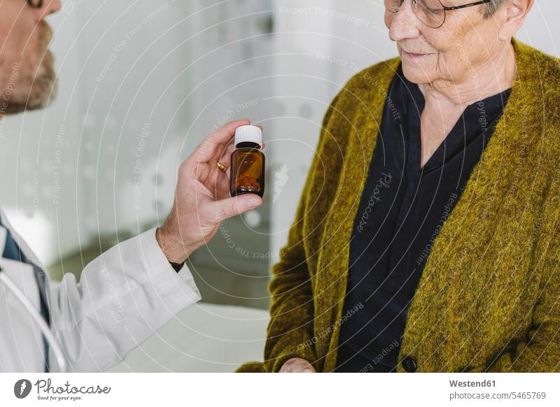 Doctor recommending pills in bottle to senior patient health healthcare Healthcare And Medicines medical medicine disease diseases illnesses sick Sickness
