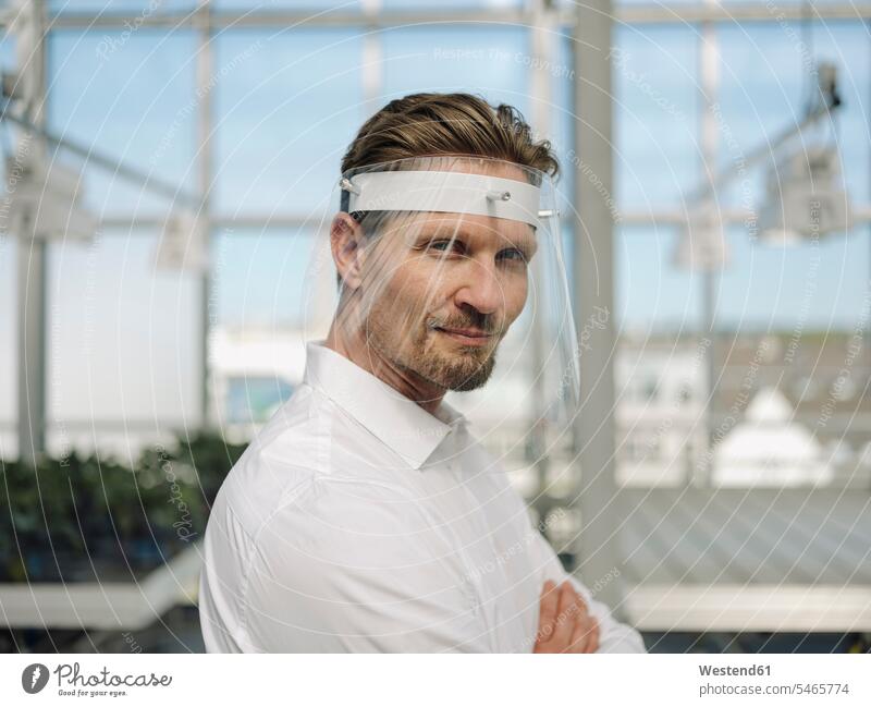Close-up of businessman wearing face shield while working in greenhouse color image colour image Germany business people businesspeople Business Professional