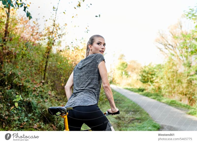 Rear view of sportive young woman with bicycle in a park females women bikes bicycles parks sporting sporty athletic Adults grown-ups grownups adult people