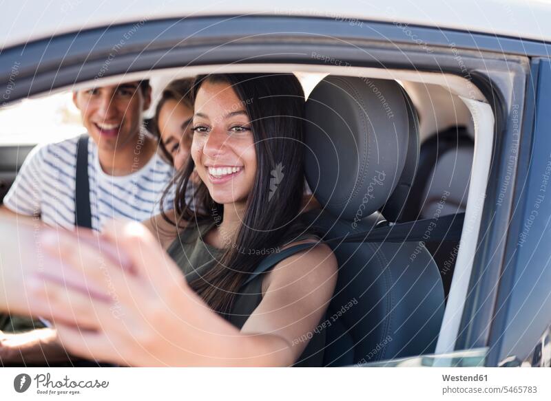 Friends having fun on a road trip, taking smartphone selfies car automobile Auto cars motorcars Automobiles excursion Getaway Trip Tours Trips friends Fun funny