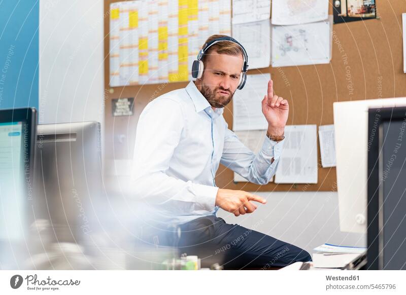 Businessman listening to music with headphones in office human human being human beings humans person persons caucasian appearance caucasian ethnicity european