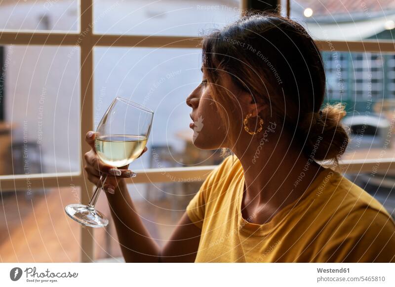Beautiful Latin woman drinking white wine at bar color image colour image casual clothing casual wear leisure wear casual clothes Casual Attire leisure activity