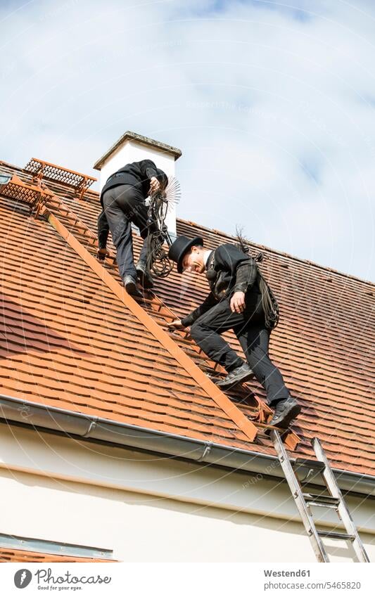 Two chimney sweeps climbing up house roof rear view back view view from the back expertise expert knowledge know-how analytic expertise know how outdoors