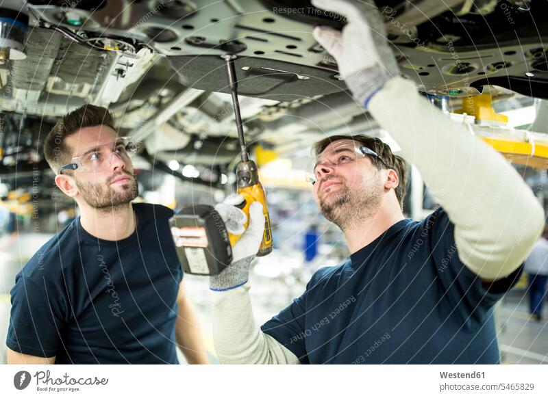 Two colleagues working at car underbody in modern factory Occupation Work job jobs profession professional occupation blue collar blue collar worker