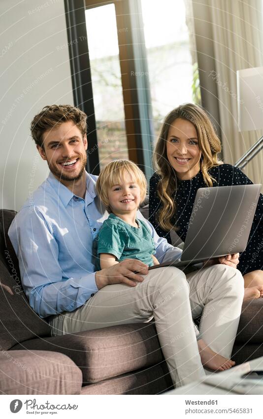 Portrait of happy parents and son sitting on sofa with laptop at home happiness couch settee sofas couches settees smiling smile Seated Laptop Computers laptops