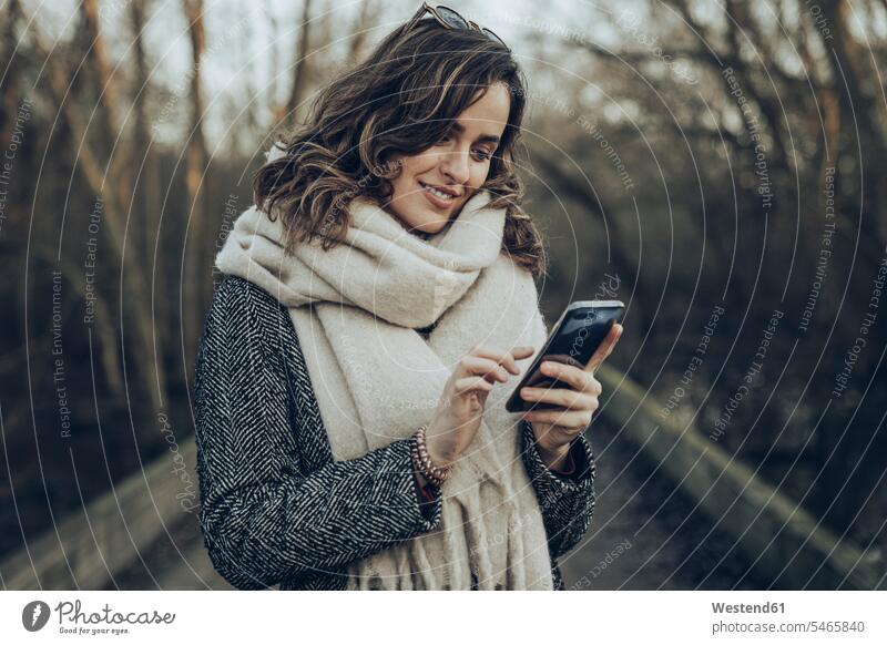 Portrait of young brunette woman using smartphone coat - garment Coats human human being human beings humans person persons caucasian appearance