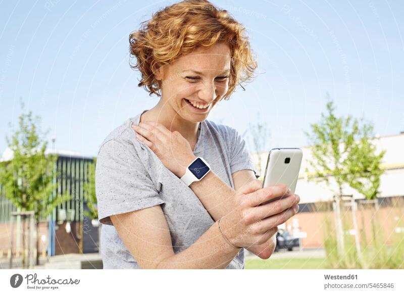 Happy young woman with smartwatch using smartphone in urban surrounding urbanity smart watch females women happiness happy Smartphone iPhone Smartphones