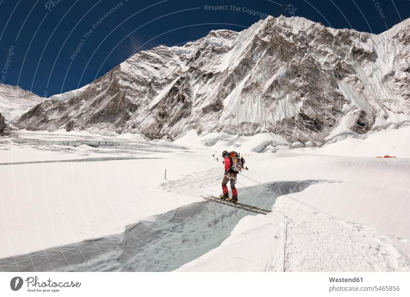 Nepal, Solo Khumbu, Everest, Sagamartha National Park, Mountaineer crossing icefall on a ladder walking going Everest region Mount Everest region mountaineering