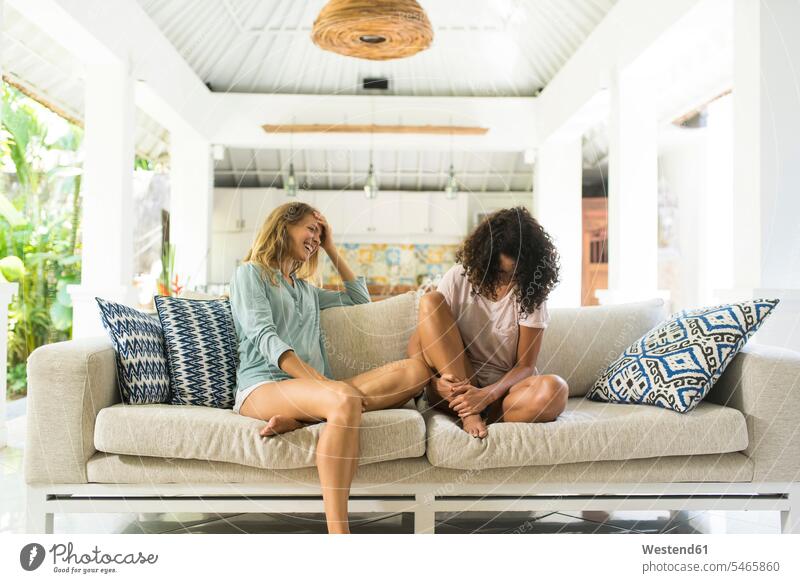 Two happy women having fun together on sofa Fun funny couch settee sofas couches settees woman females female friends happiness Adults grown-ups grownups adult