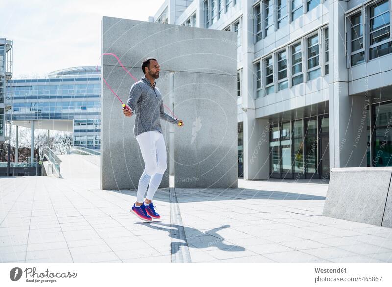 Man skipping rope in the city jumping rope skip rope jump rope Jumping Ropes man men males town cities towns Adults grown-ups grownups adult people persons