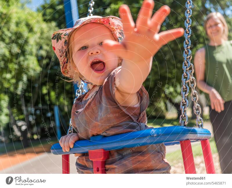 Portrait of happy little girl with her mother on playground playground swing swing set swings swingset grab grabbing grip scream shout shouting summer time