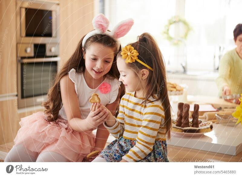 Two girls looking at cookie in kitchen Biscuit Cookie Cooky Cookies Biscuits sister sisters eyeing females Pastry Pastries Sweet Food sweet foods food and drink