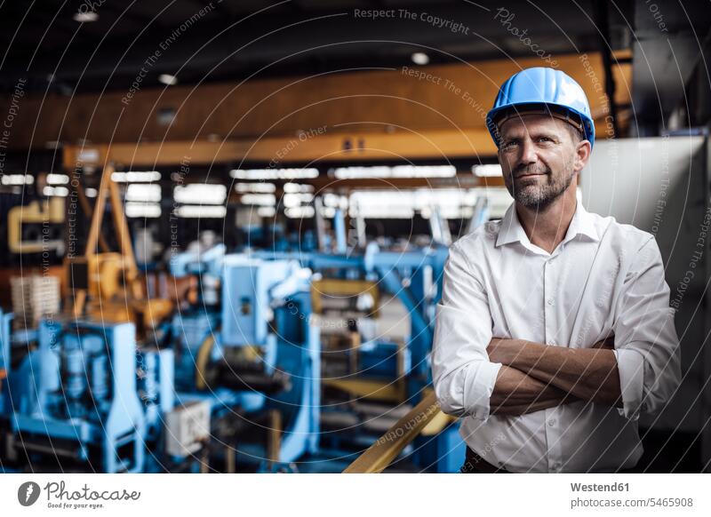 Smiling male entrepreneur with arms crossed standing at factory color image colour image indoors indoor shot indoor shots interior interior view Interiors