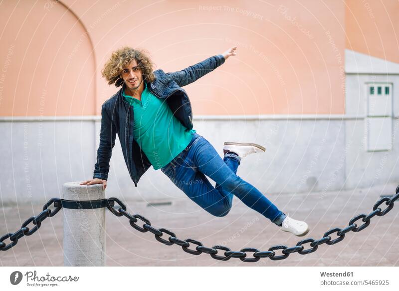 Portrait of smiling young man jumping over chain outdoors portrait portraits Leaping chains jumps mid-air midair mid air leaning rested on Vitality Verve vigour