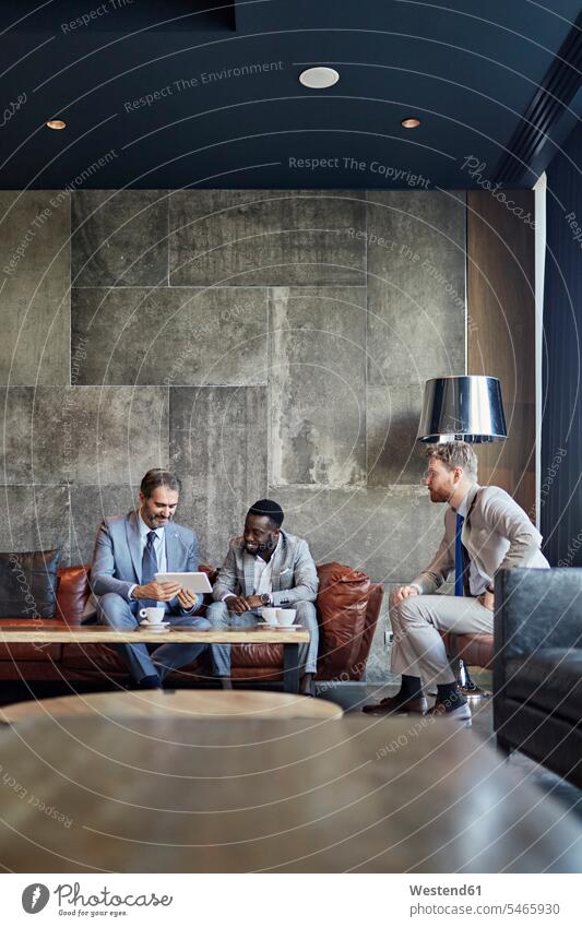 Three businessmen sitting in hotel lobby with tablet business life business world business person businesspeople associate associates business associate
