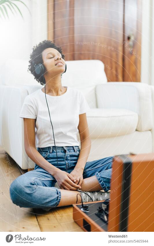 Young woman sitting on grounf listening music from record player, using headphones sitting on ground Sitting On The Floor Sitting On Floor vinyl record records