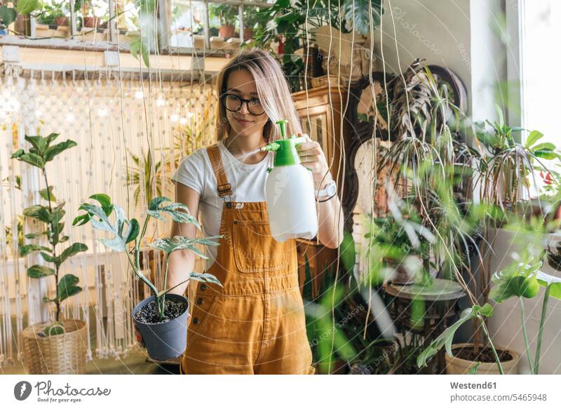 Young woman caring for plants in a small shop Occupation Work job jobs profession professional occupation flower pot flower pots flowerpots Eye Glasses
