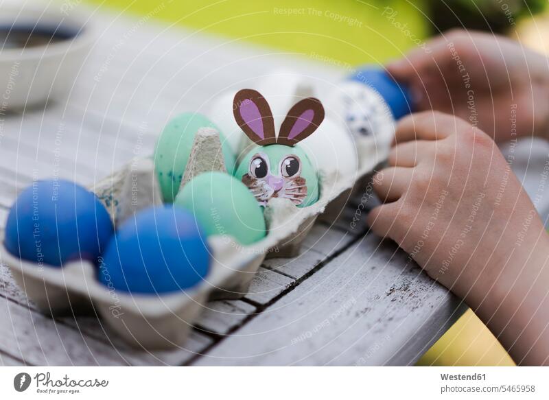 Close-up of girl decorating Easter egg on garden table human human being human beings humans person persons caucasian appearance caucasian ethnicity european 1