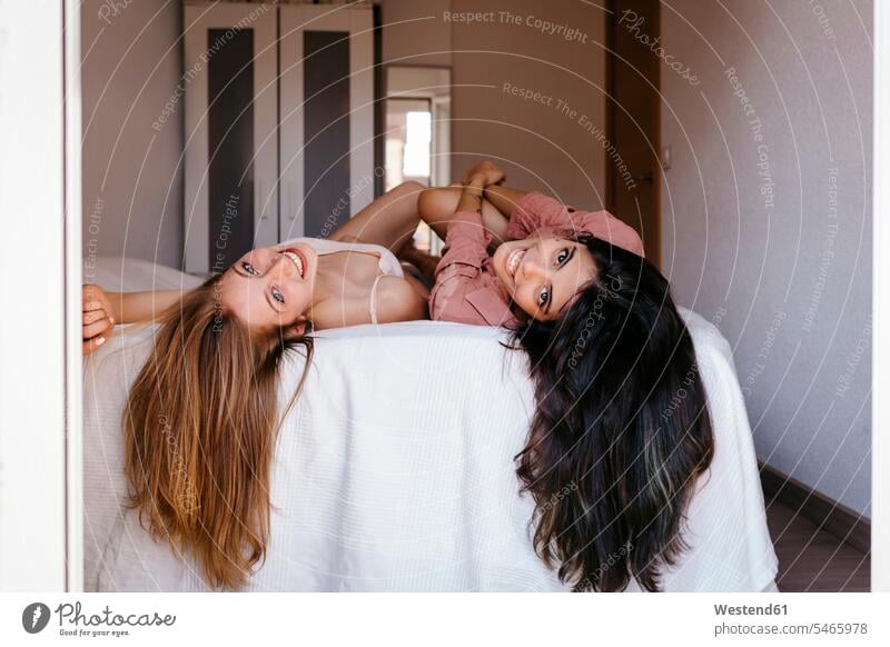 Young friends with long hair lying on bed at home color image colour image indoors indoor shot indoor shots interior interior view Interiors day daylight shot