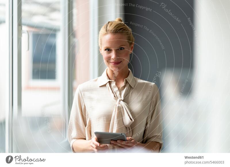 Portrait of smiling young businesswoman with tablet at the window Occupation Work job jobs profession professional occupation business life business world