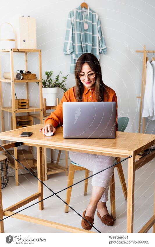 Female fashion designer working at home sitting at desk with laptop human human being human beings humans person persons caucasian appearance