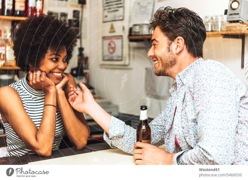 Man holding beer bottle touching female bartender while flirting with her at bar counter color image colour image indoors indoor shot indoor shots interior